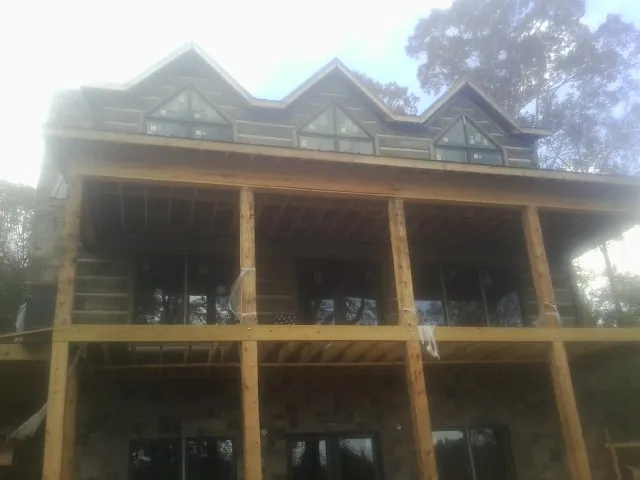 Dormers and porch framing on a large log home under construction — Roof Coating work by our crew in Quilcene