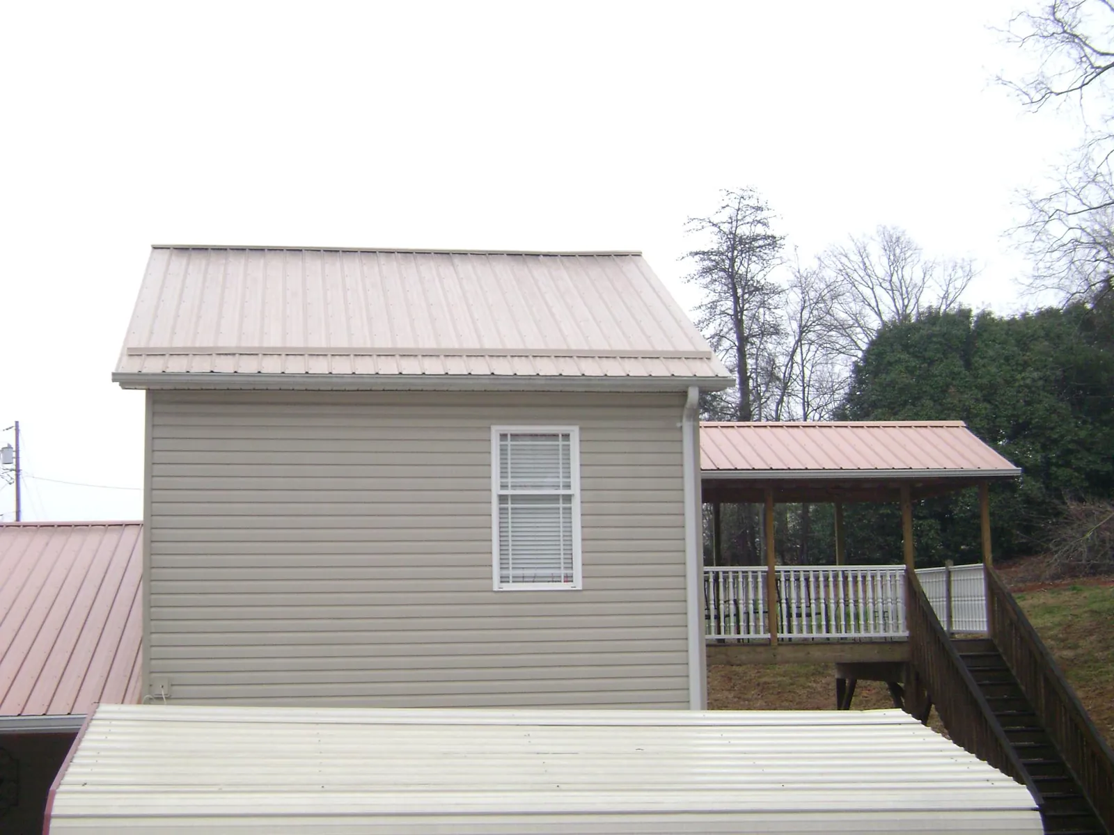 Tan metal roofs on a two story addition and attached porch, from a Roof Replacement job in Quilcene