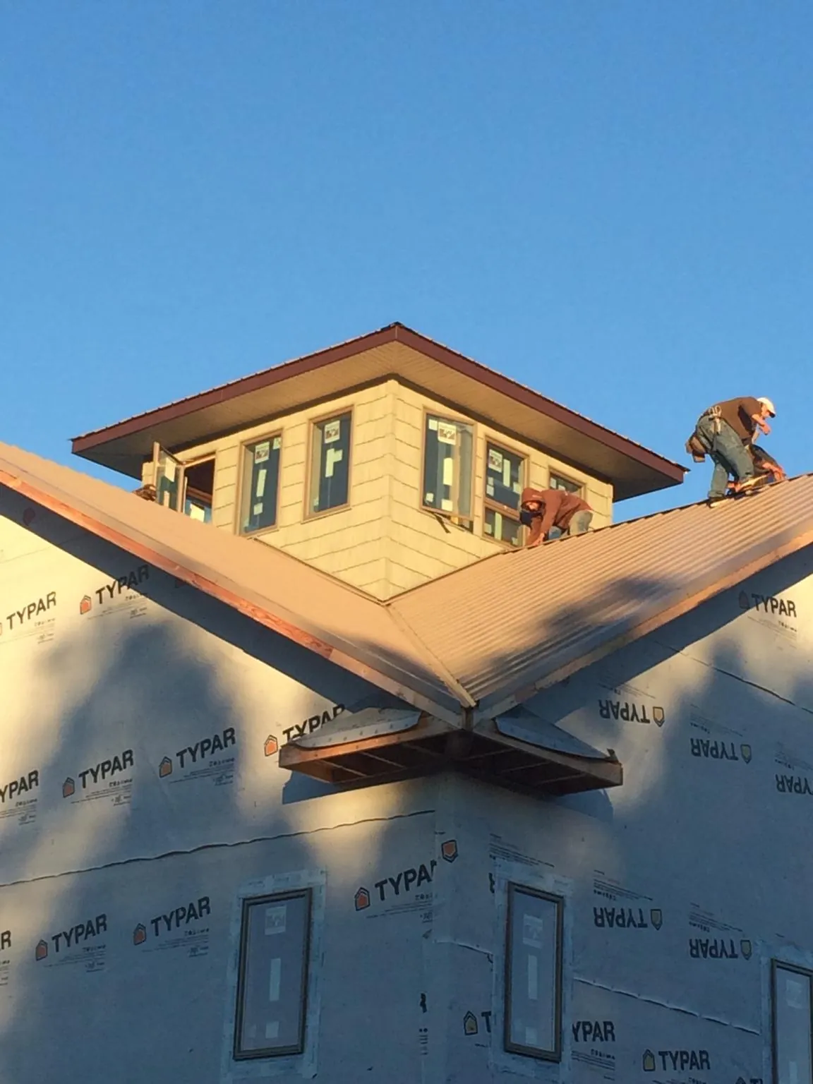 Roofers working around a rooftop cupola on a new metal roof at sunset — Roof Waterproofing in Quilcene by Roofing Brothers
